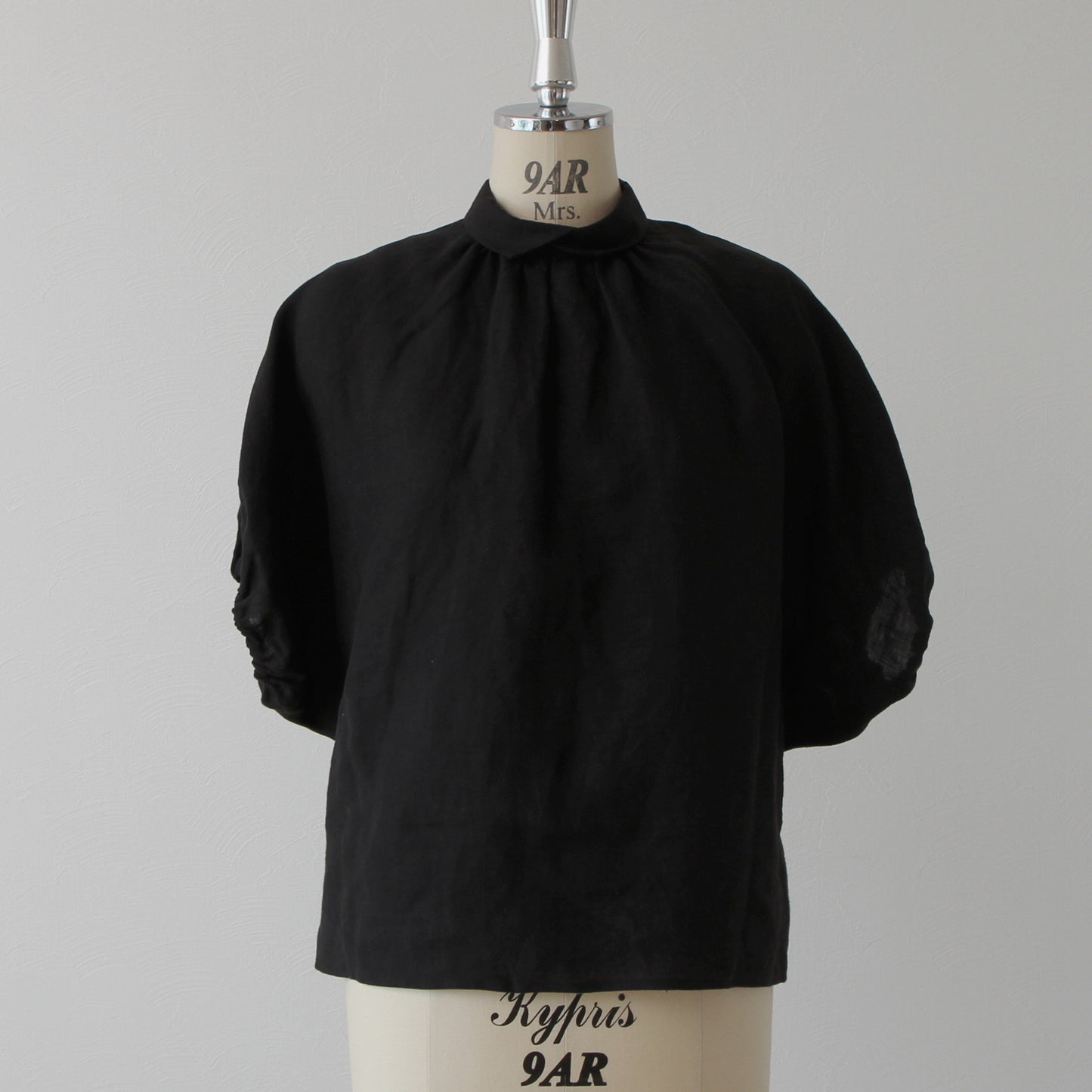 A sophisticated and cute clerical collar with back covered buttons and voluminous sleeves. French linen blouse with half-length sleeves/black